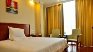 Ein Hotelzimmer mit einem großen Bett, zwei Sesseln, einem kleinen Tisch und einem Bild an der Wand.