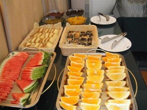 Un buffet proposant une variété d’aliments, notamment des tranches de pastèque, des tranches d’orange et d’autres fruits.