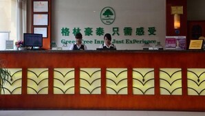 Ein Empfangsschalter mit einem Schild für GreenTree Inn und dem Slogan "Just Experience".