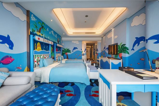Una habitación infantil con un mural temático marino, una litera, un escritorio y una zona de estar acogedora.