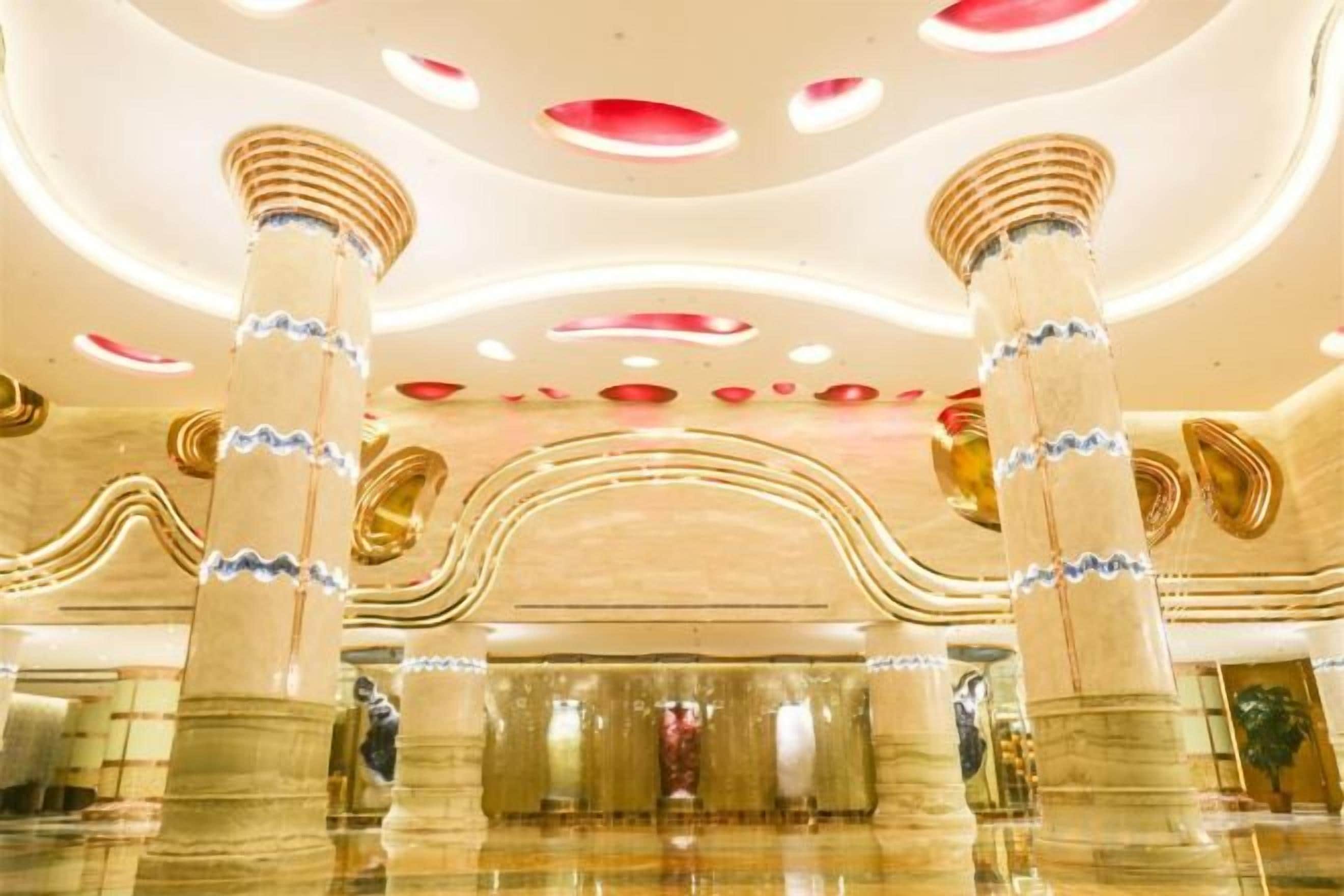 Un hall d’entrée orné de colonnes en marbre, doté d’un plafond incurvé avec des luminaires circulaires et d’un sol réfléchissant.