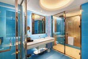 Un baño moderno con ducha envuelta en vidrio, un espejo grande y un lavabo blanco.