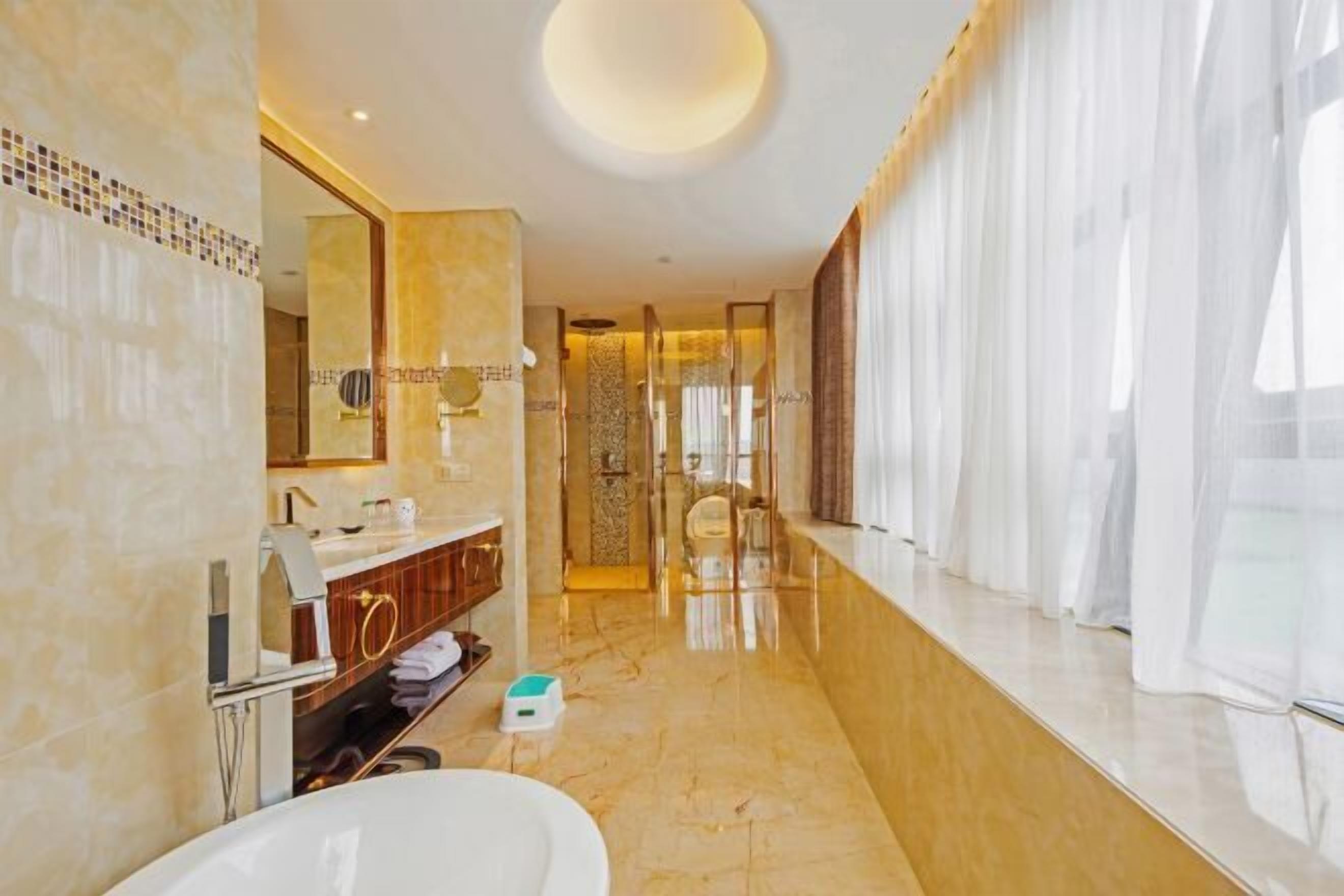 A modern bathroom with a large mirror, a bathtub, a vanity with a sink, and a shower area.