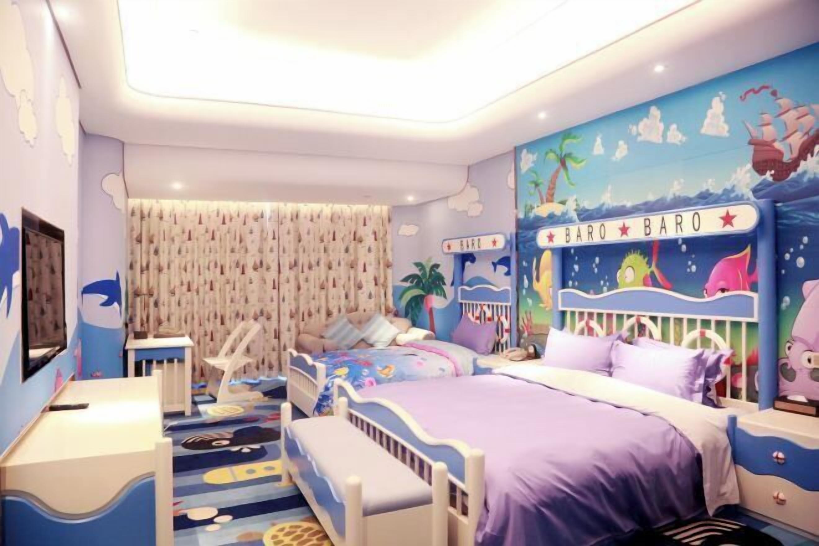 Habitación infantil con dos camas, un escritorio y un mural de una playa.