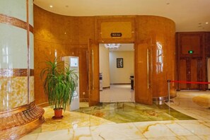 A hotel lobby with a marble floor, a reception desk, and a potted plant. - Oriental Grand Hotel Shaoxing (Shaoxing)