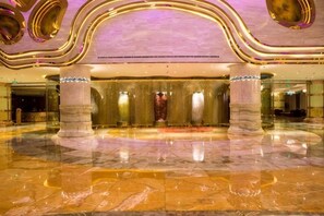 A spacious lobby with marble flooring, large columns, and a modern ceiling design.