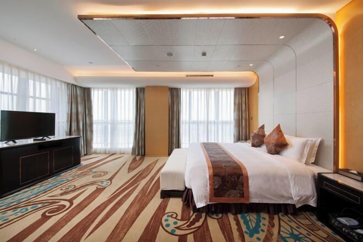 Habitación de hotel con una cama grande, un televisor de pantalla plana, un escritorio y piso alfombrado.