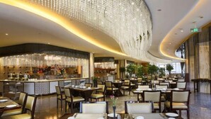 Un comedor amplio con varias mesas y sillas, una zona de bar con mostrador, y un techo con adornos colgantes.