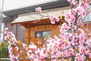 A wooden building with a sign, surrounded by blooming pink flowers. - Shenghao Seasons Hotel (Huimin)