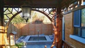 A wooden cabin with a stone patio, a hot tub, and a wooden deck. - Shenghao Seasons Hotel (Huimin)