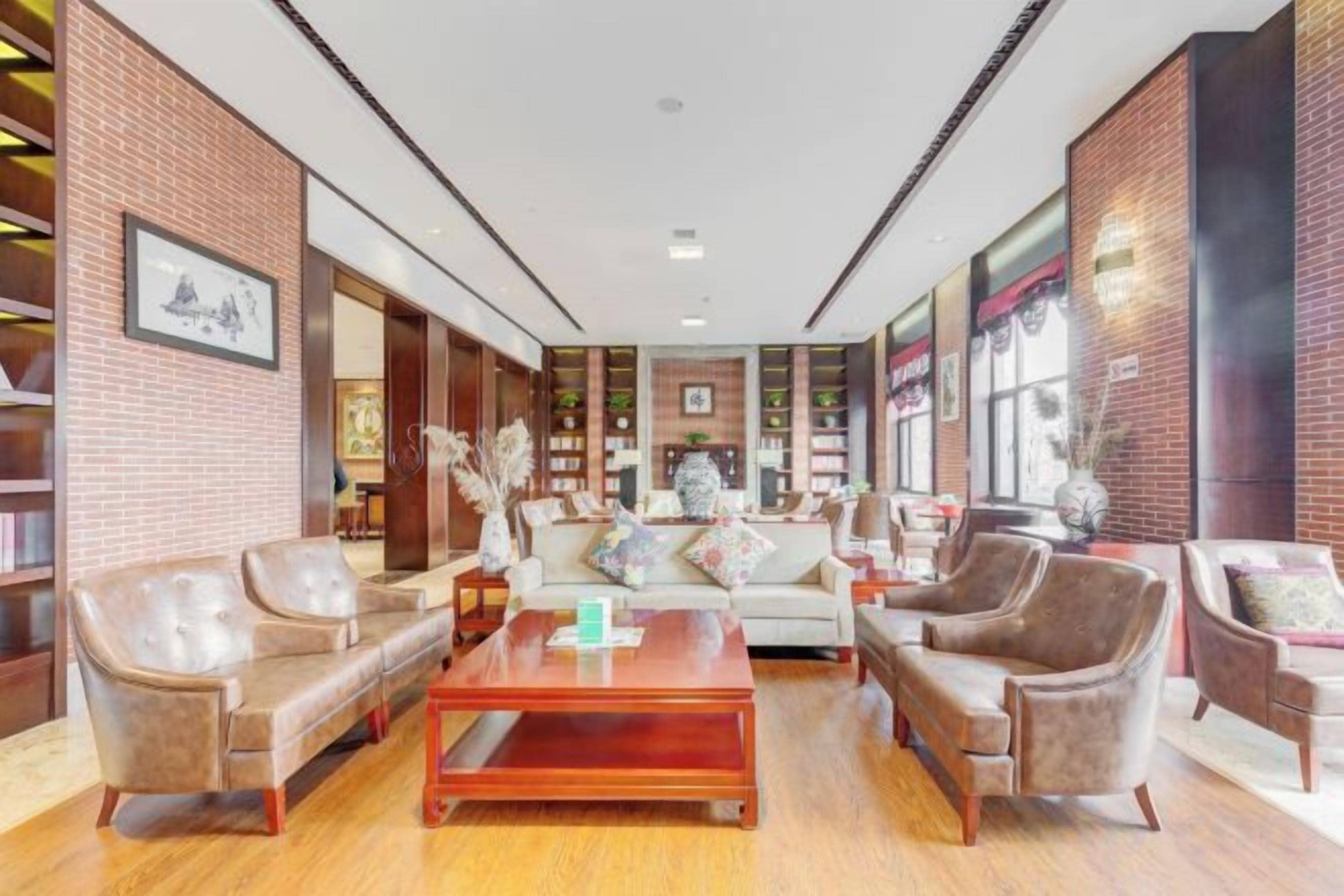 A spacious lobby with leather sofas, a wooden coffee table, and brick walls.