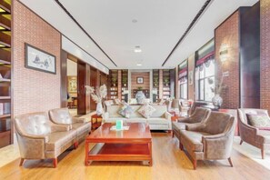 Un lobby amplio con sofás de cuero, una mesa de centro de madera y paredes de ladrillo.