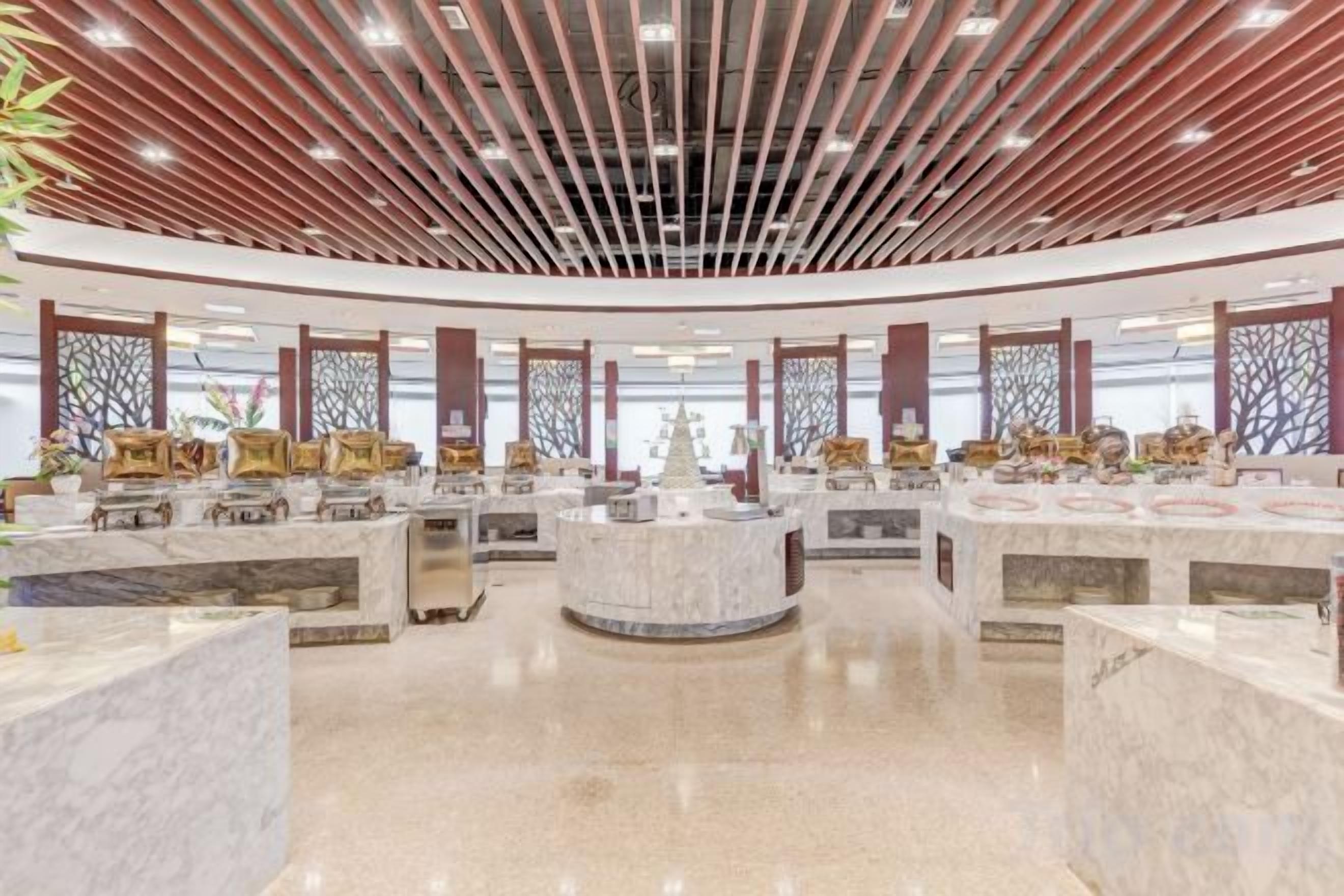 A spacious lobby with marble counters and a high ceiling with wooden slats.