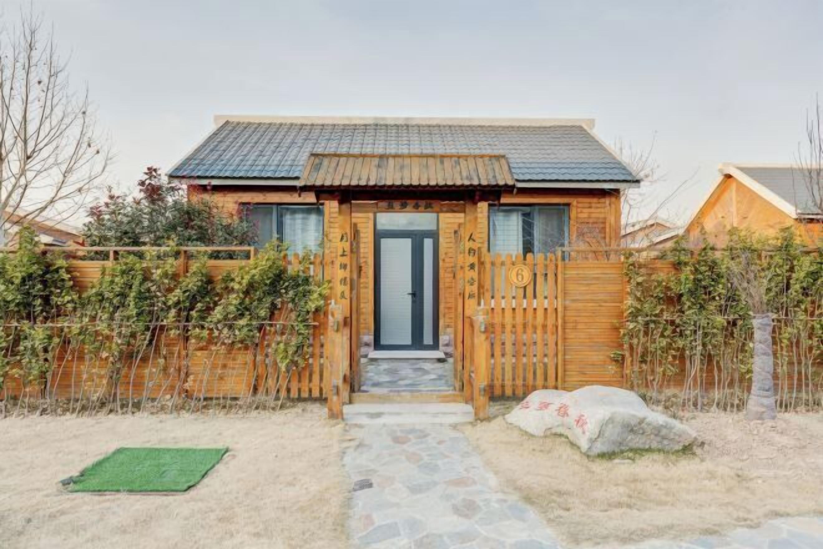 Una casa de madera con techo de tejas, un portón de madera y un camino de piedra que conduce a la entrada.