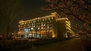 A multi-story hotel with illuminated windows and a well-lit facade at night. - Shenghao Seasons Hotel (Huimin)