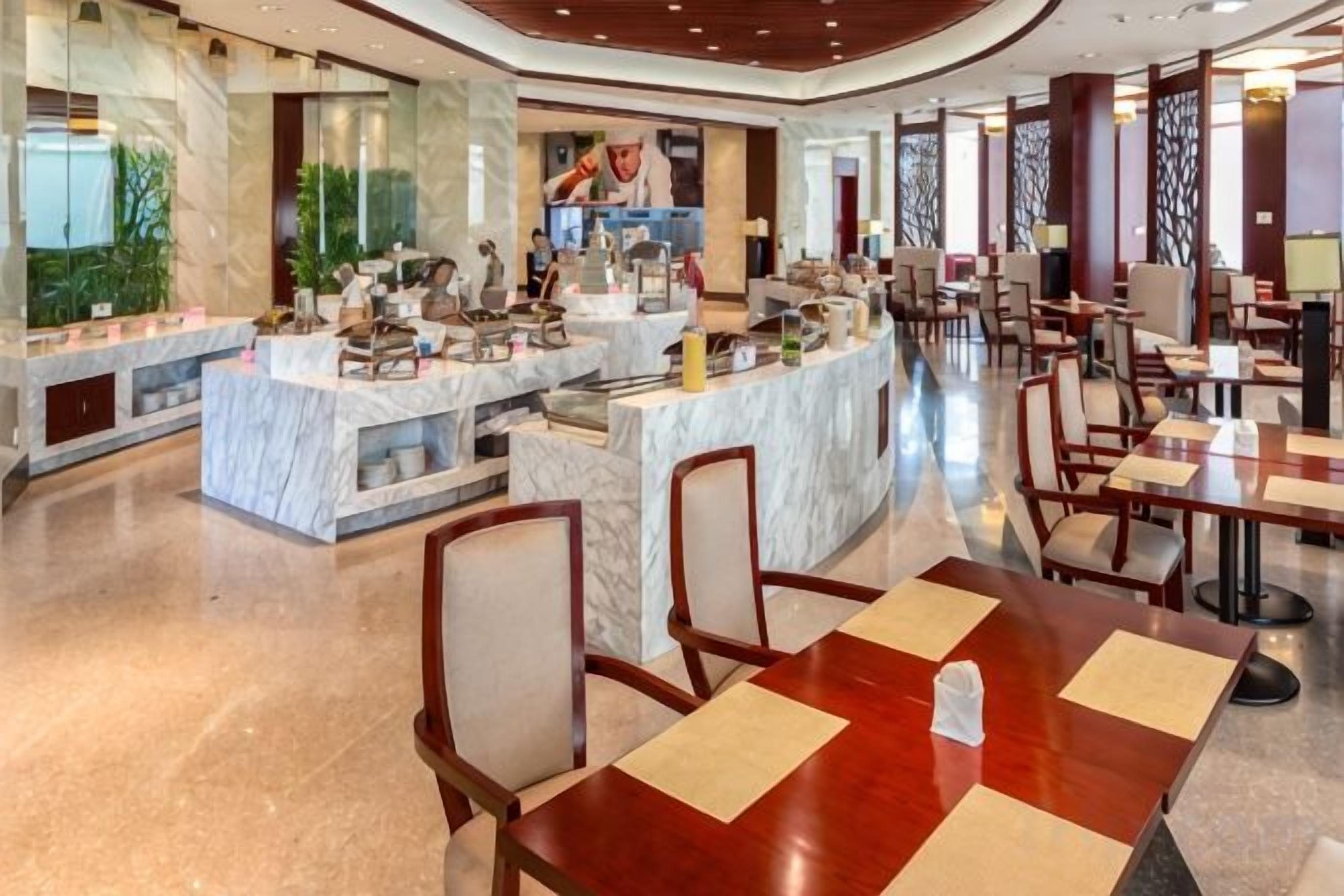 A spacious hotel lobby with marble counters, seating areas, and a central bar.