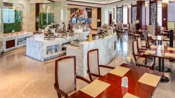 A spacious hotel lobby with marble counters, seating areas, and a central bar.