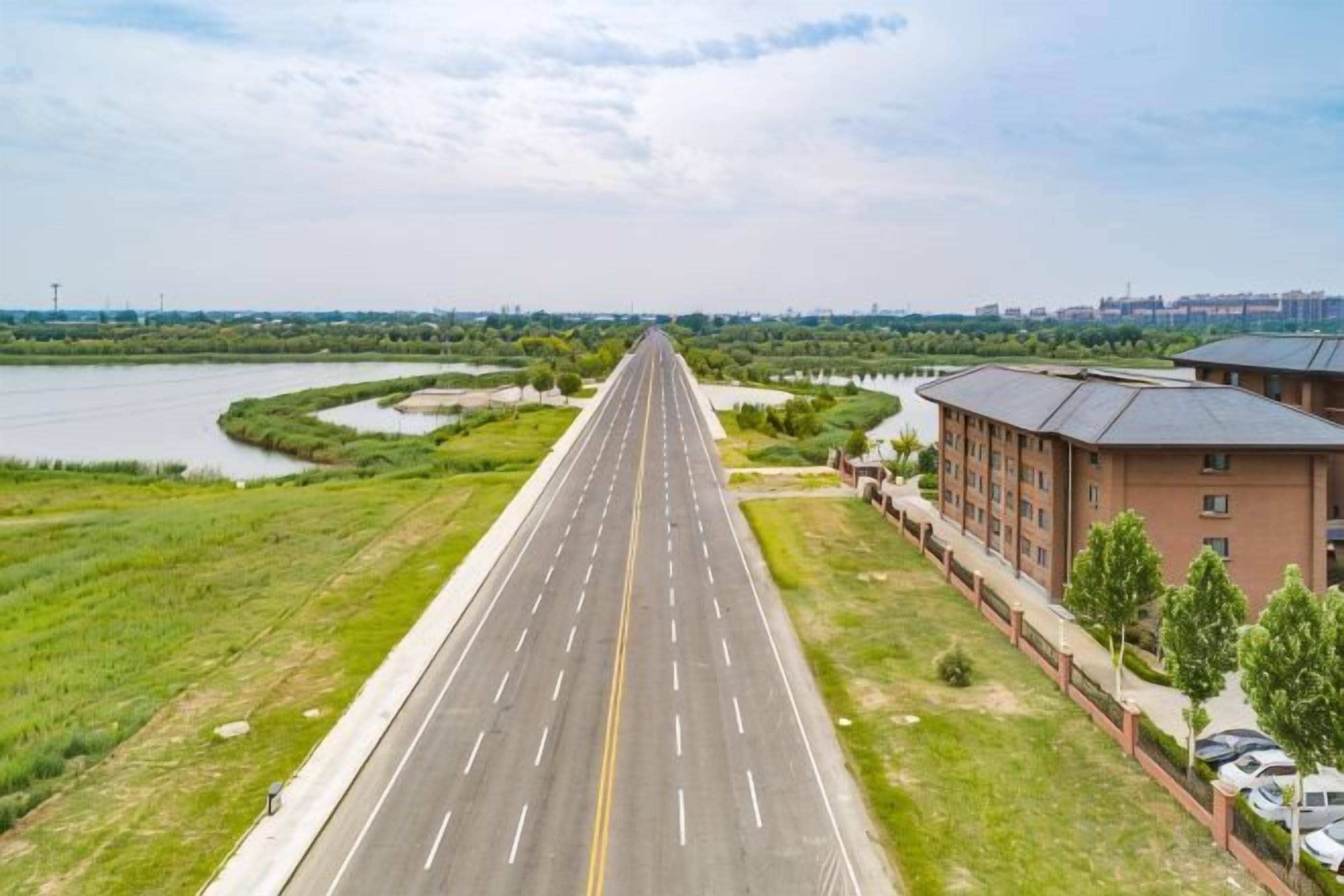 A straight road with a river on one side and a building on the other.