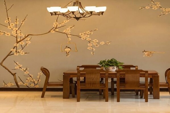 Uma sala de jantar com uma mesa e cadeiras de madeira, um candelabro e decorações nas paredes.