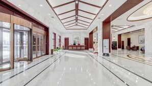 A spacious lobby with a polished marble floor, a reception desk, and a large glass entrance. - Shenghao Seasons Hotel (Huimin)