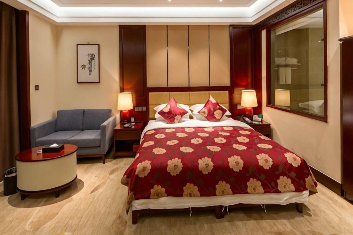 Een hotelkamer met een groot bed, een bank, een nachtkastje en een bureau.