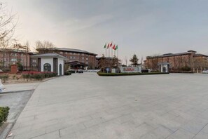 Un edificio grande con un patio empedrado, varias banderas y un letrero con caracteres chinos.