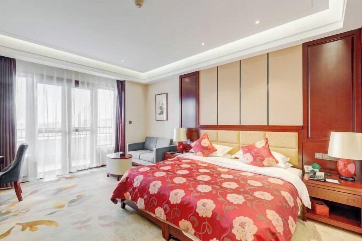 Una habitación de hotel con una cama grande, un sofá, un escritorio y vistas a la ciudad.