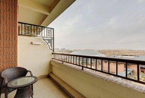 Uma varanda com vista para a cidade, uma mesa pequena e uma cadeira.