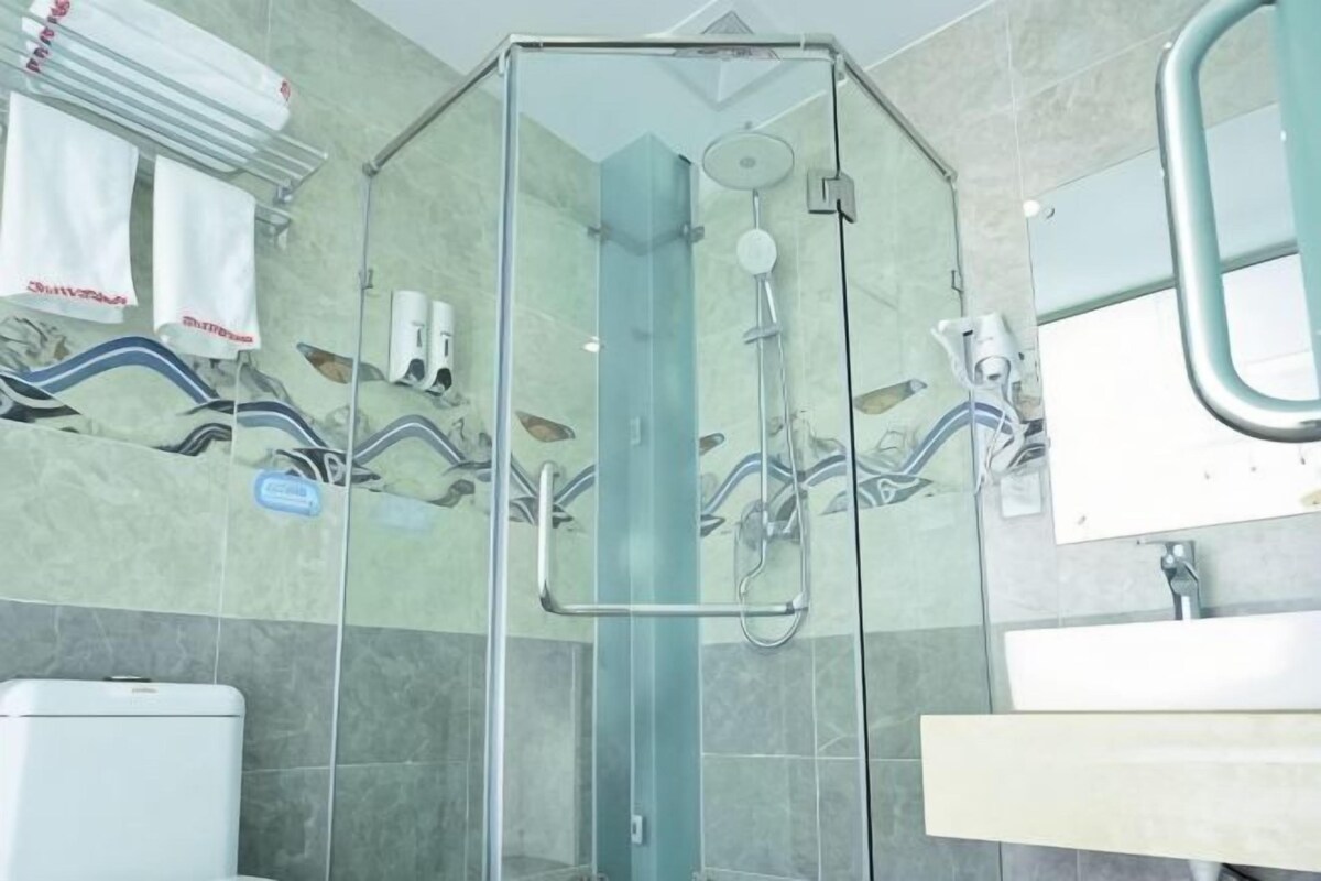 Un baño con cabina de ducha de vidrio, un lavamanos y un espejo.