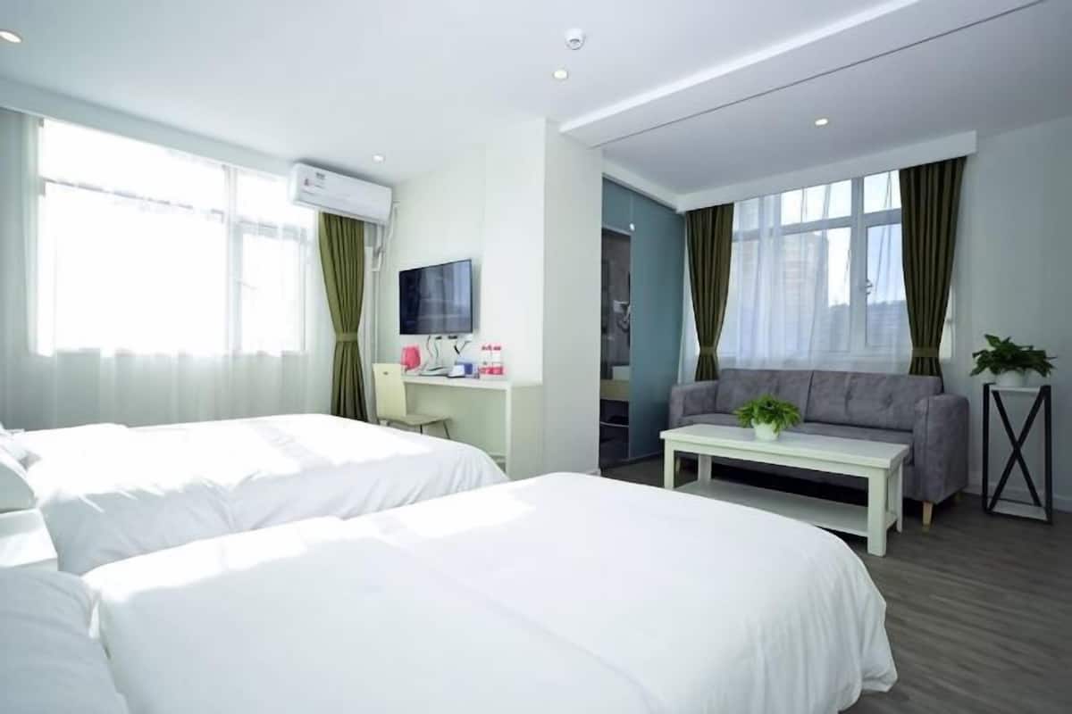 Une chambre d’hôtel avec deux lits, un bureau avec un ordinateur, une télévision et un canapé.