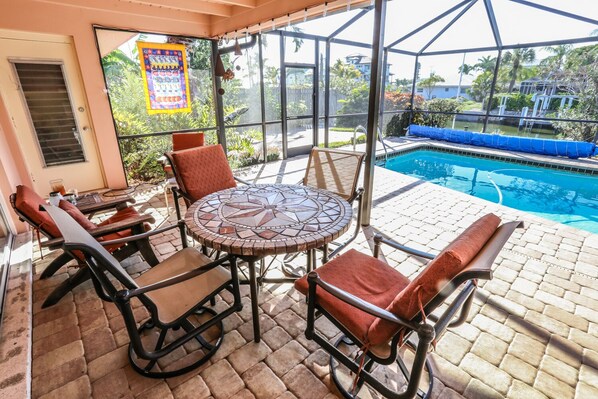 Relax in a tranquil outdoor space with a mosaic-tiled table and cushioned chairs, adjacent to a swimming pool.