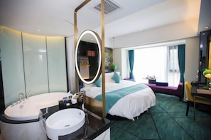 A hotel room with a large bed, a separate bathroom with a bathtub, a desk, and a window with curtains. - Yunman Life Hotel (Xuyong)