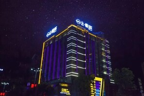 A multi-story building with illuminated signage and vertical lines on the facade. - Yunman Life Hotel (Xuyong)