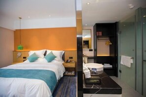 A hotel room with a bed, bedside table, and a bathroom with a sink and mirror. - Yunman Life Hotel (Xuyong)