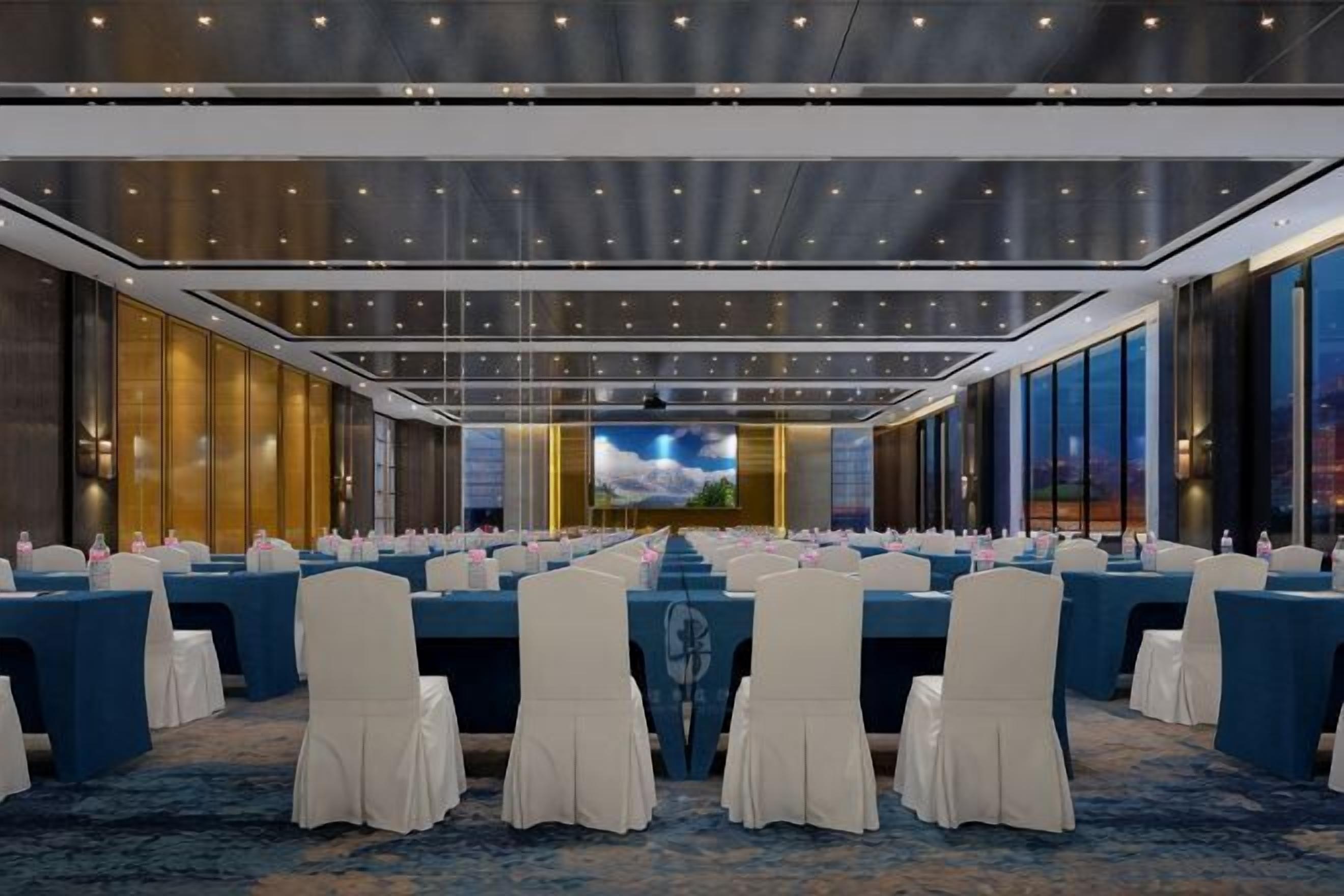 A conference room with a long table, chairs, and a large screen.