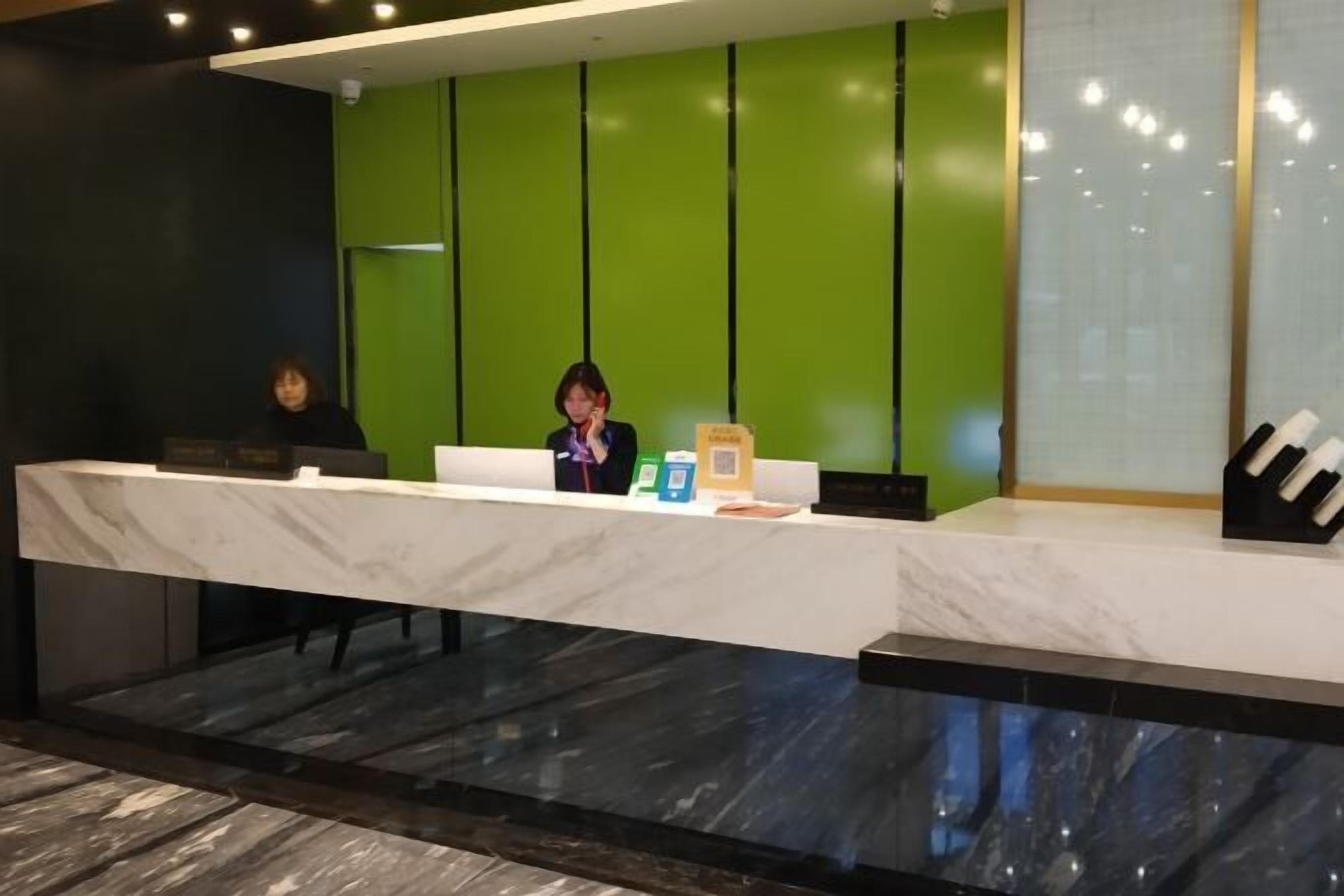 A reception desk with a marble counter, a green wall, and a black floor.