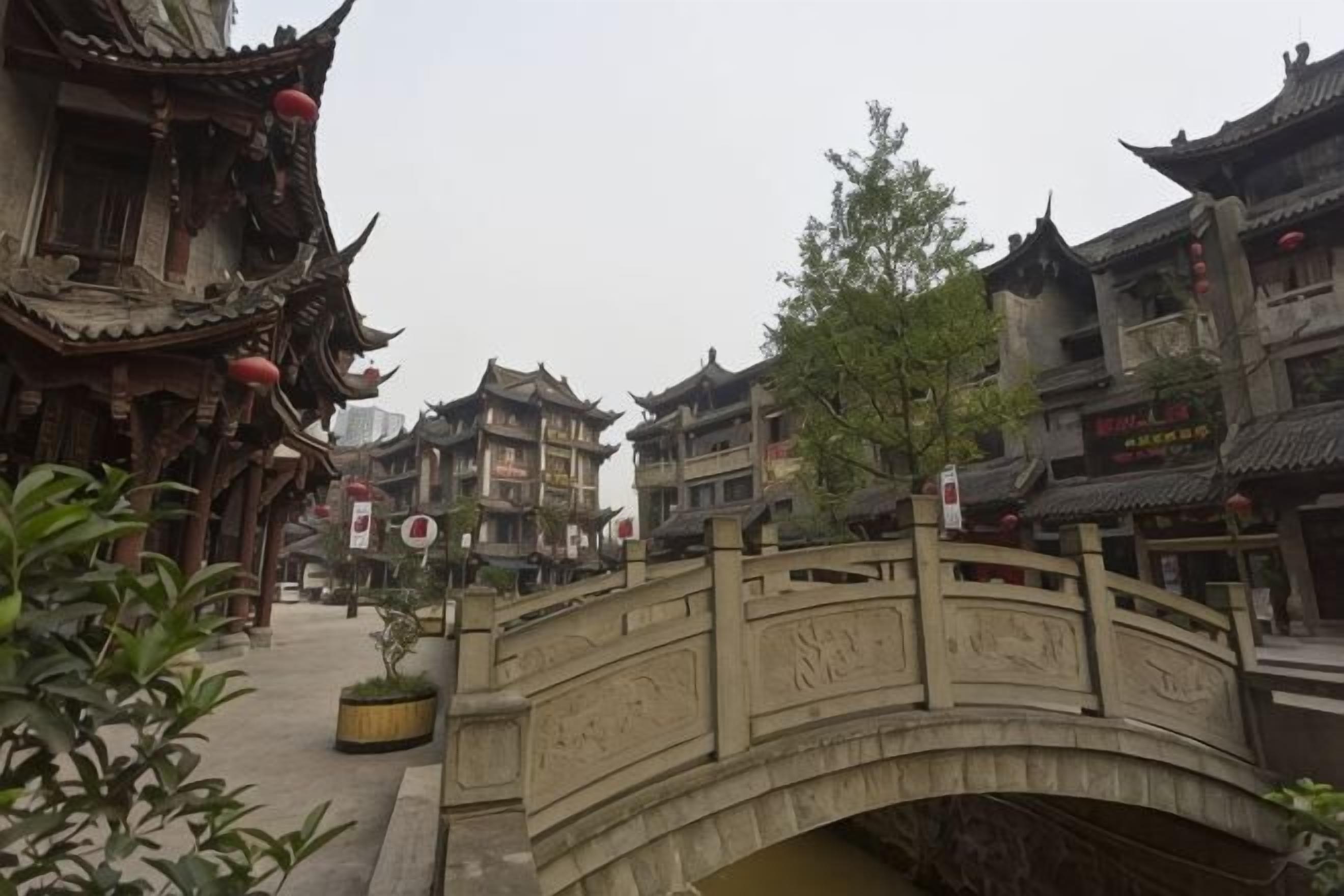 A traditional Chinese courtyard with a stone bridge, ornate buildings, and a signboard.