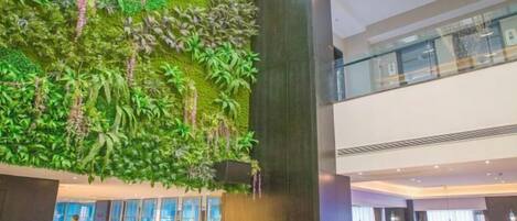 A lobby with a vertical garden wall, a reception desk, and seating areas.
