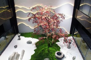 A modern indoor garden with a tree, rocks, and a small pond. - Yunman Life Hotel (Xuyong)