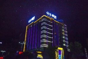 A multi-story building with illuminated signage and vertical lines. - Yunman Life Hotel (Xuyong)