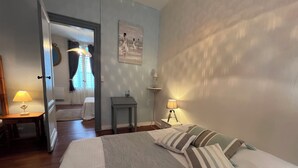 Une chambre à coucher comprenant un lit, des tables de chevet, une commode, une porte et un couloir menant à une autre pièce.