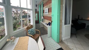 Un intérieur chaleureux avec un coin repas, une cuisine aux volets verts et une vue sur le jardin extérieur.