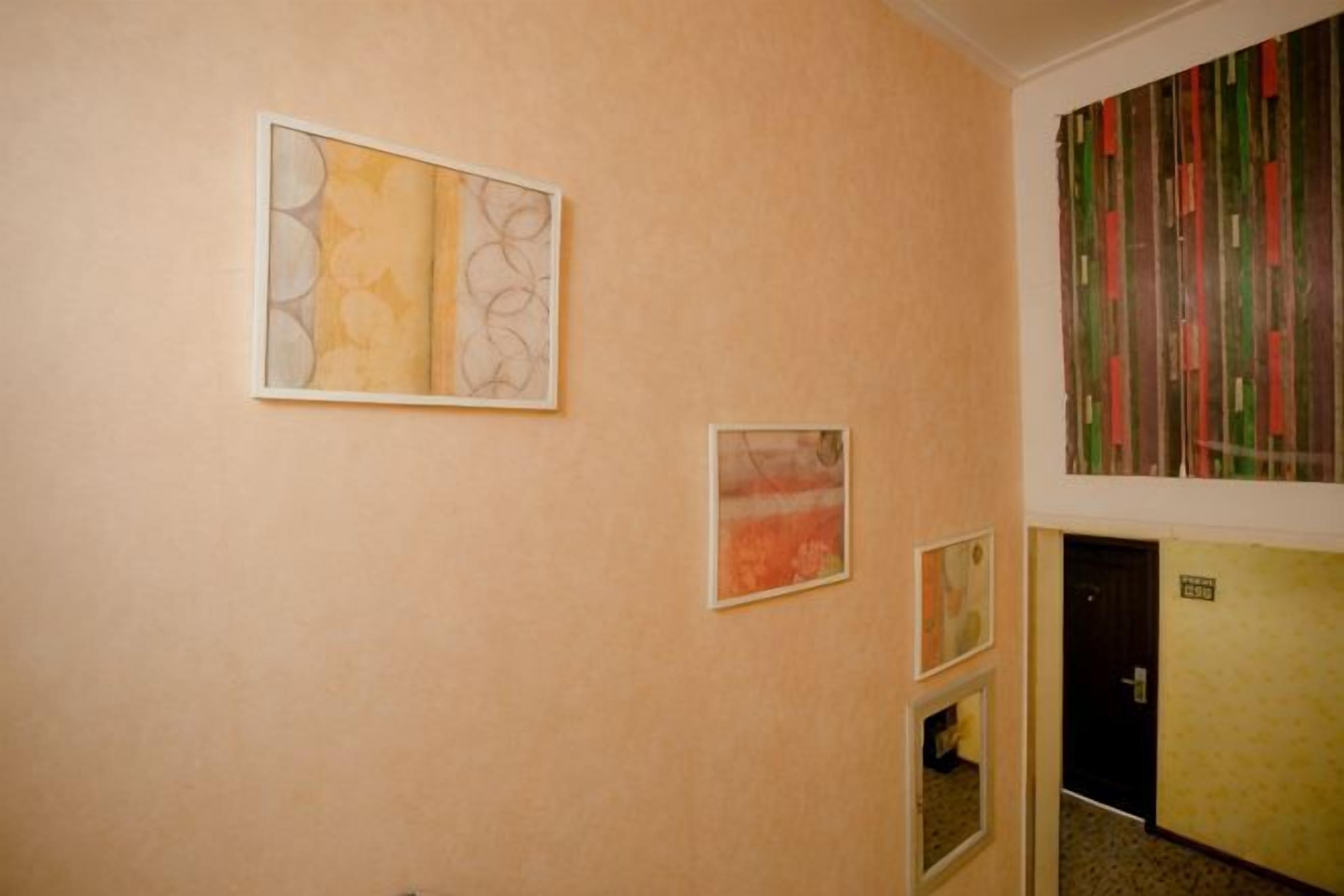 A hallway with artwork on the walls, a door, and a carpeted floor.