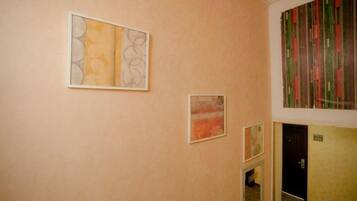 A hallway with artwork on the walls, a door, and a carpeted floor.