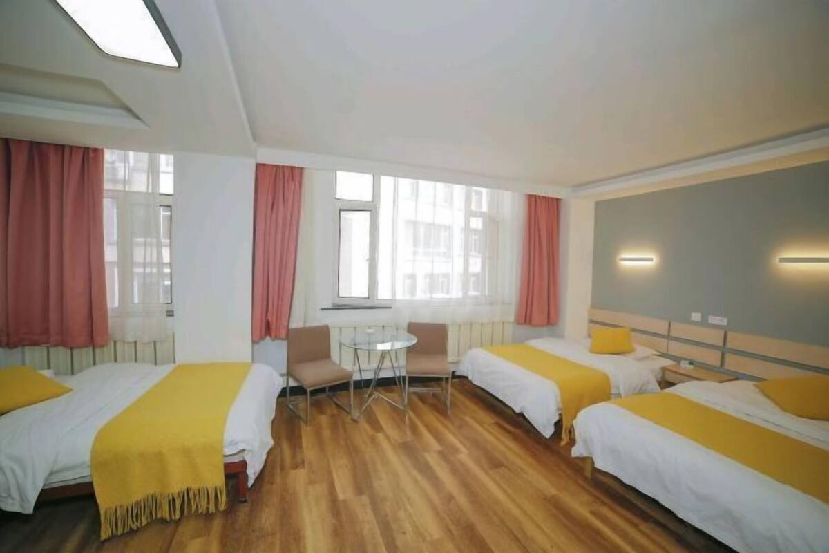 A hotel room with two beds, a small table, chairs, and a window.