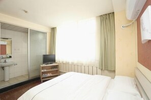 A hotel room with a bed, a TV on a stand, a mirror, a window with curtains, and a radiator. - Changchun Yuanyuan Business Hotel (Jida Second Hospital Yatai Hospital Area Branch) (Changchun)