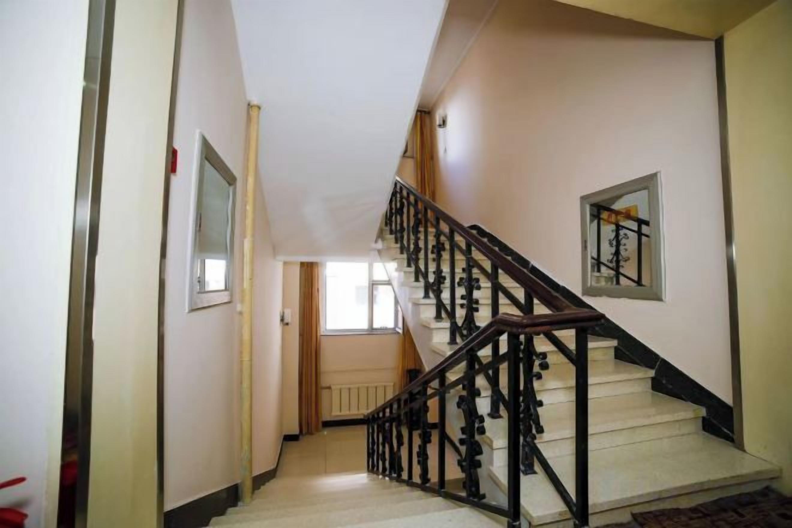 A staircase with a wooden handrail and a radiator on the wall.
