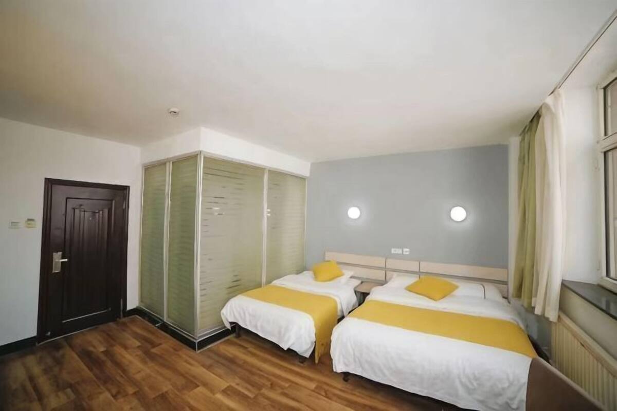 A hotel room with two beds, a wardrobe, and a window.