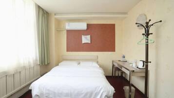 Une chambre d’hôtel avec un lit, un bureau doté d’une bouilloire et un porte-manteau.