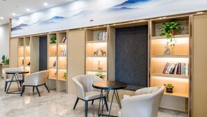 A modern library with bookshelves, seating, and decorative items. - Rezen Select Bellehaute (Suzhou)